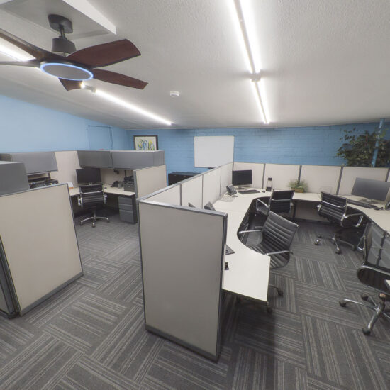 Modern office space with grey and white cubicles, black chairs, and blue walls
